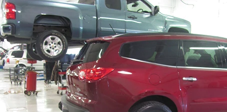 Automotive facility cleaning—vehicles inside a service garage, including a pickup truck on a lift for maintenance.