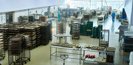 Food and beverage processing flooring—large clean facility with smooth coated floors, food trays, and racks for production.